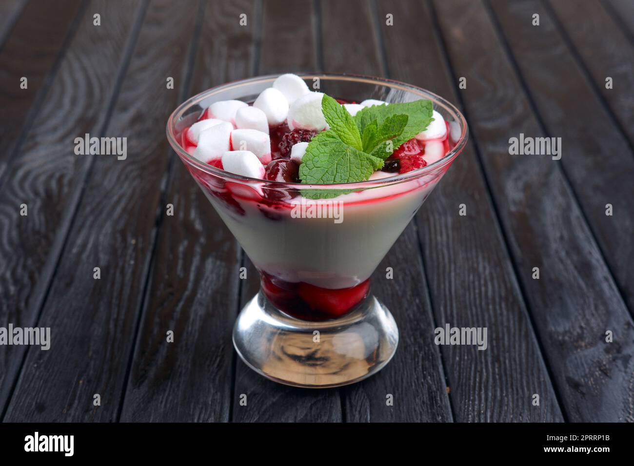 Un bicchiere di youghurt con marshmallow e lamponi decorato con foglie di menta Foto Stock