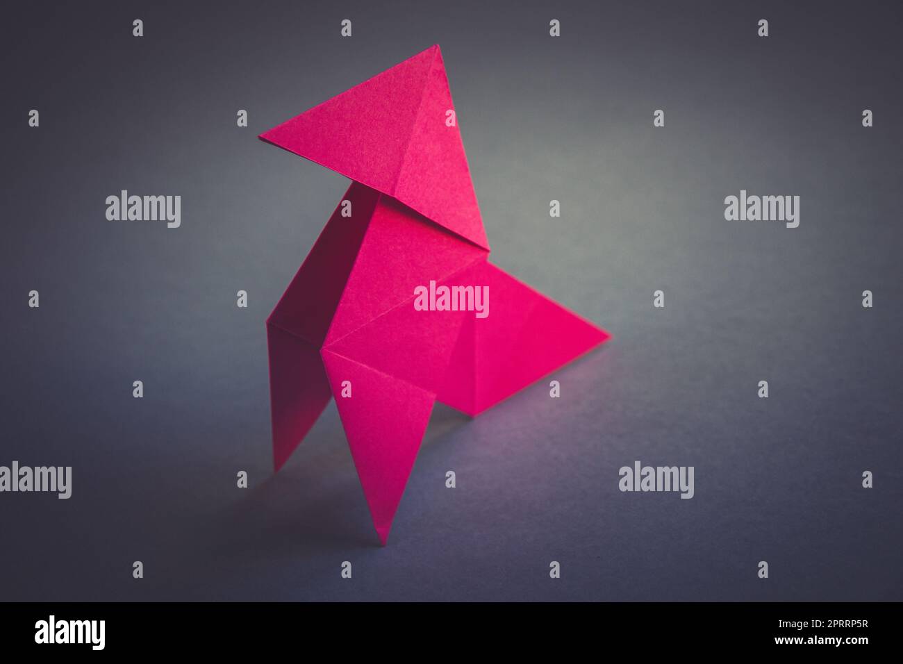 Carta rosa gallina origami isolato su uno sfondo grigio Foto Stock