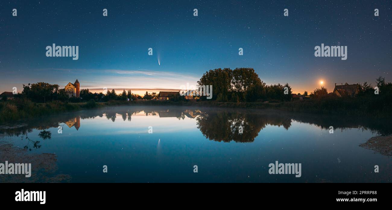 Dobrush, Bielorussia. La cometa Neoswise C2020f3 e la Luna ascendente in cielo stellato di notte riflessa nelle acque del piccolo lago. Foto Stock