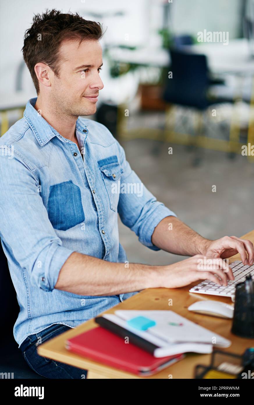 Amando lo sguardo di questi disegni. Un giovane bello che lavora alla sua scrivania in un ufficio. Foto Stock