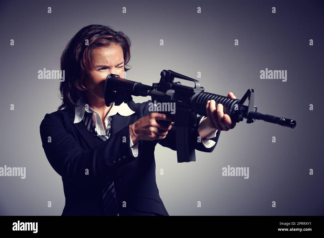 Shell ti porta fuori. Una giovane donna d'affari che punta con un fucile. Foto Stock