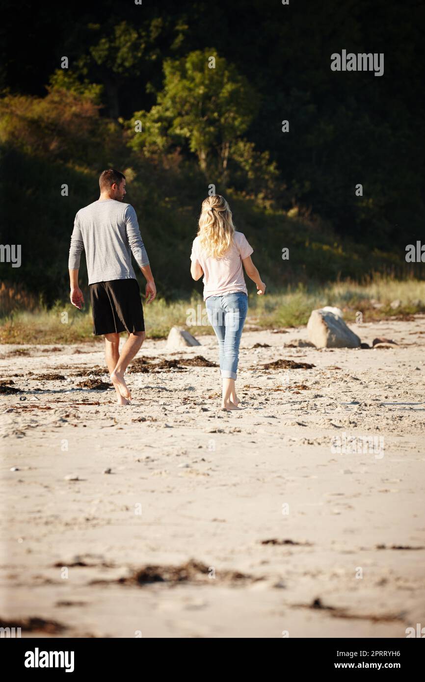 Trascorrere un tempo perfetto insieme. Ripresa di una giovane coppia che cammina lungo una spiaggia sabbiosa. Foto Stock