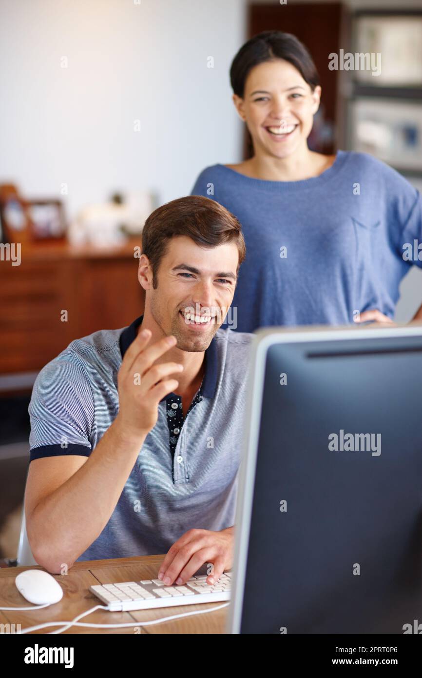 Trovare i video online più divertenti. Una giovane coppia che usa un computer a casa. Foto Stock