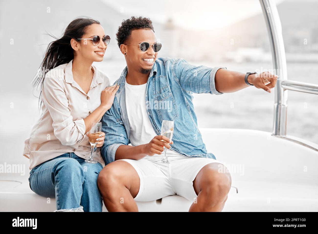 Felice coppia su una barca di lusso con un bicchiere di champagne in estate o in mare. Giovane uomo e donna che beve vino mentre naviga su uno yacht o naviga in vacanze costose. Foto Stock
