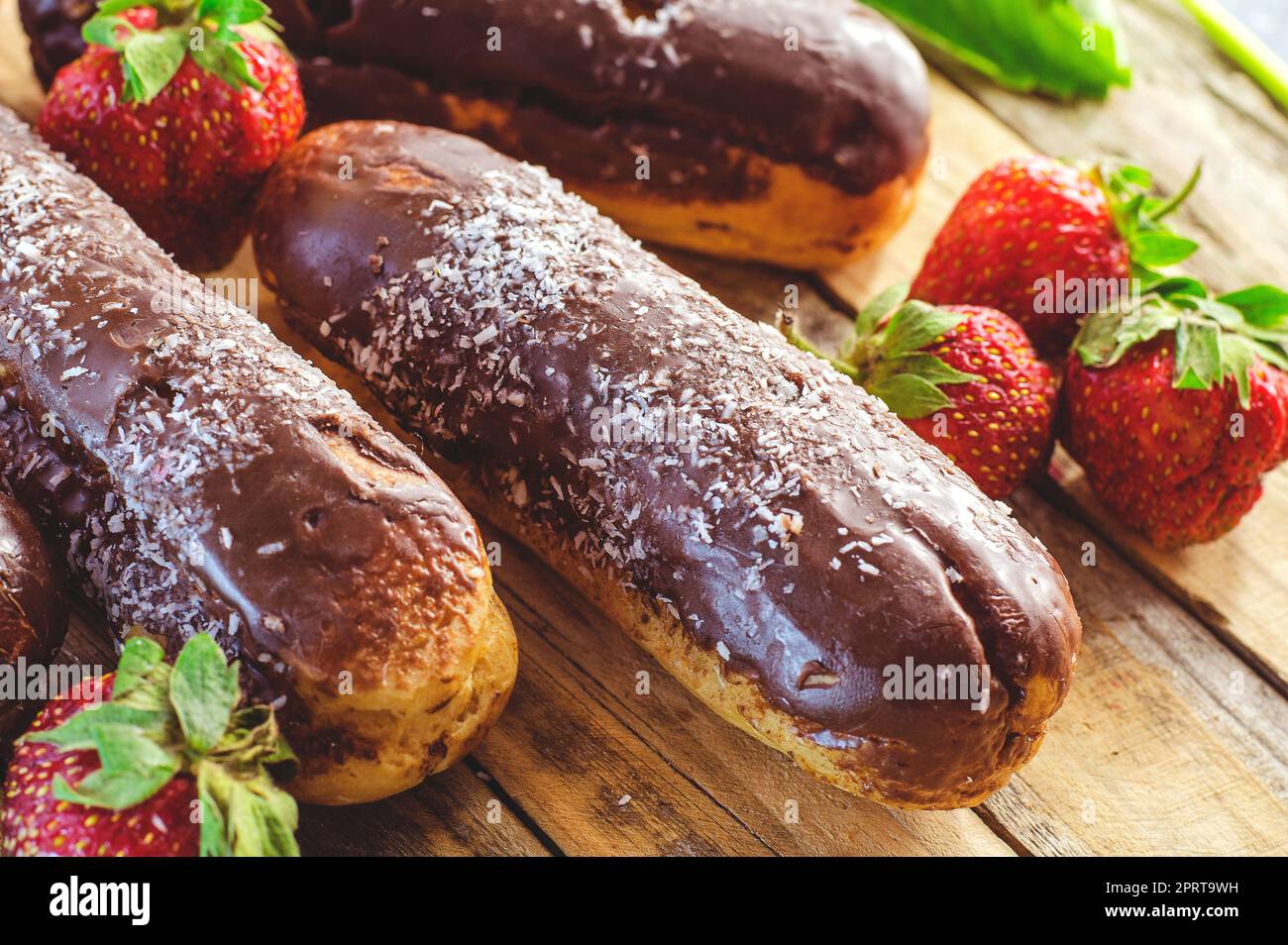 Profiterole al cioccolato e fragole fresche su un tavolo di legno Foto Stock