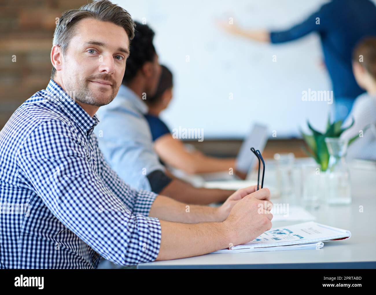 Stare al passo con la curva creativa del business. Un designer maturo che sorride alla macchina fotografica in una sala riunioni. Foto Stock