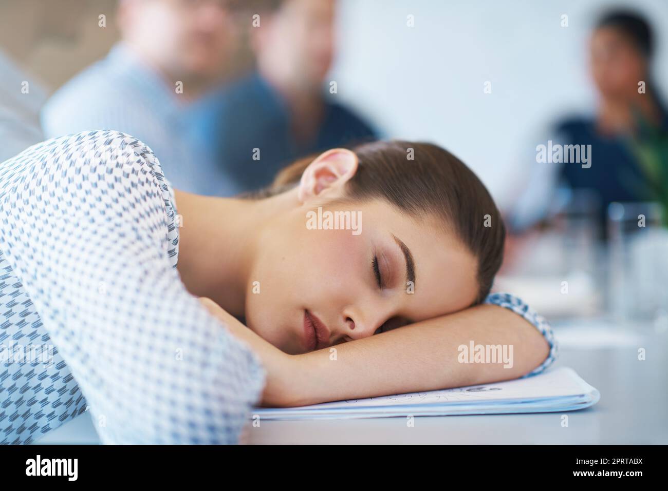 Ha funzionato dal vapore... una donna d'affari esausta sdraiata con la testa sulle sue braccia durante una riunione. Foto Stock