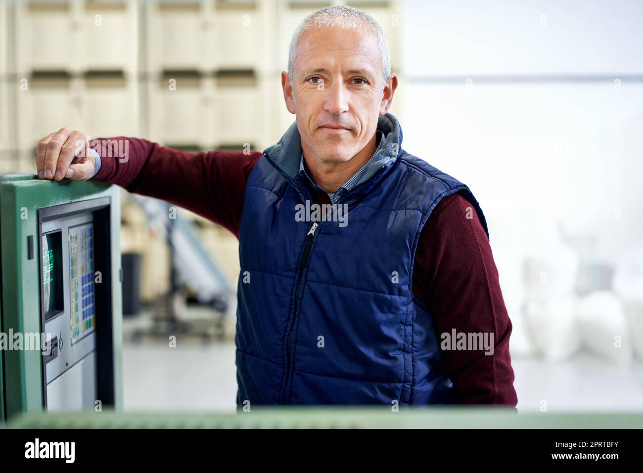 Non assicurarsi che questo macchinario funzioni regolarmente. Ritratto di un uomo maturo in piedi accanto a un macchinario in una fabbrica. Foto Stock