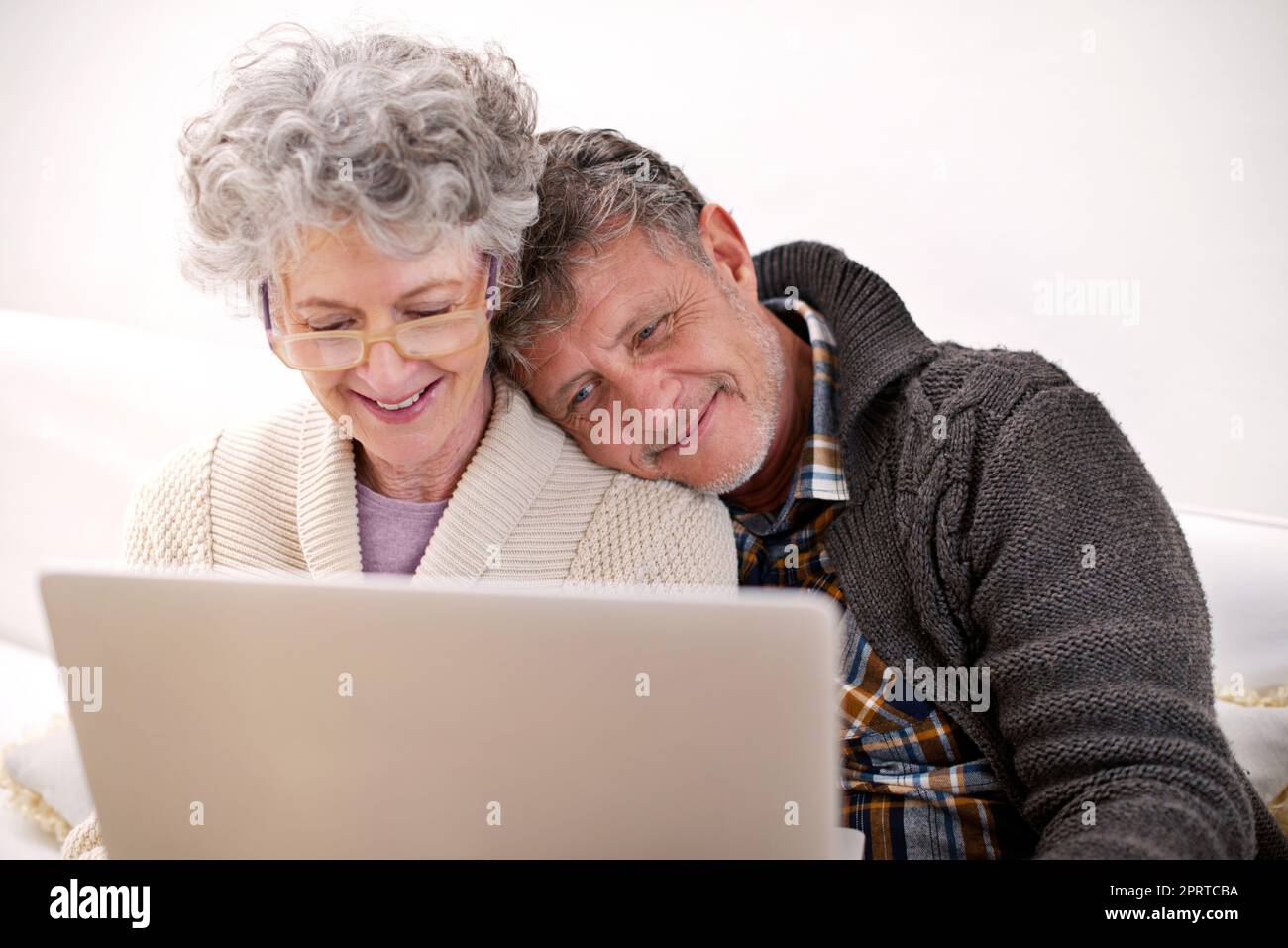 Ama coccolarsi con sua moglie, una coppia anziana che usa un notebook nel salotto di casa. Foto Stock