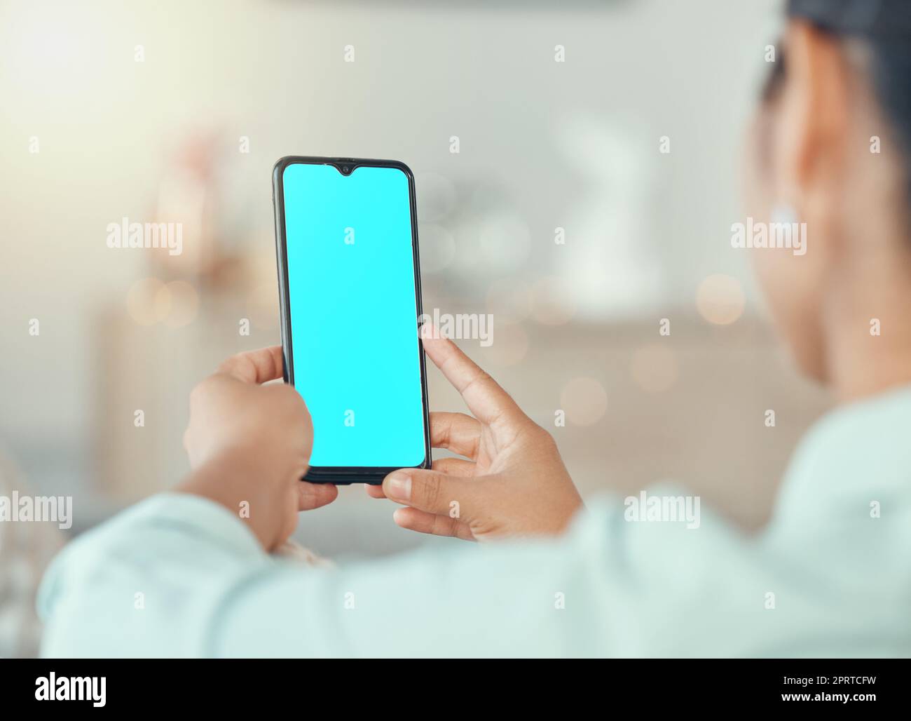 Mockup, marketing e pubblicità su un telefono con uno schermo blu nelle mani di una donna in casa sua. Posizionamento del prodotto, logo e marchio su un display mobile per il design di un sito Web creativo o di una home page Foto Stock