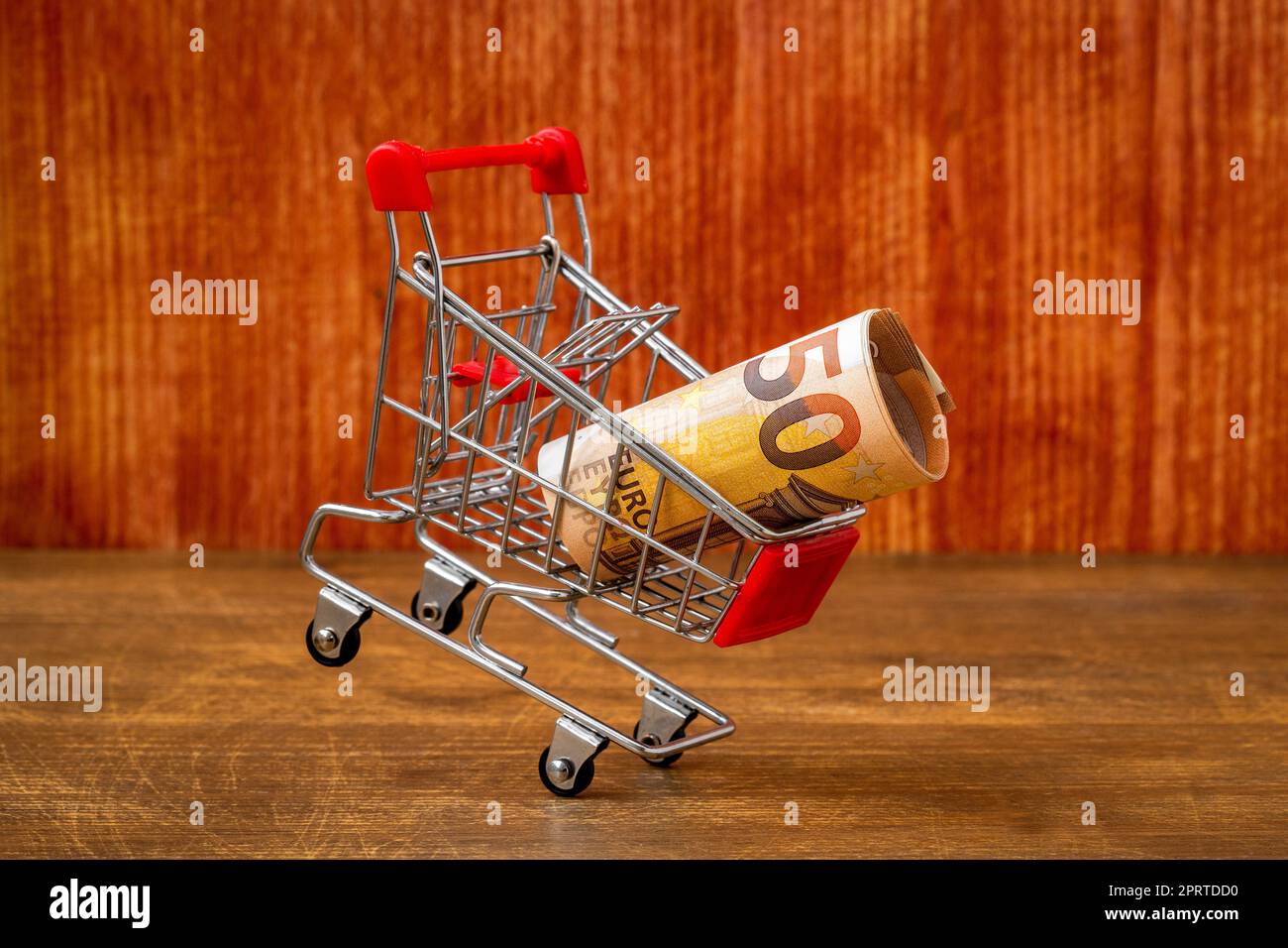 Carrello cadente con un euro di denaro su sfondo di legno Foto Stock