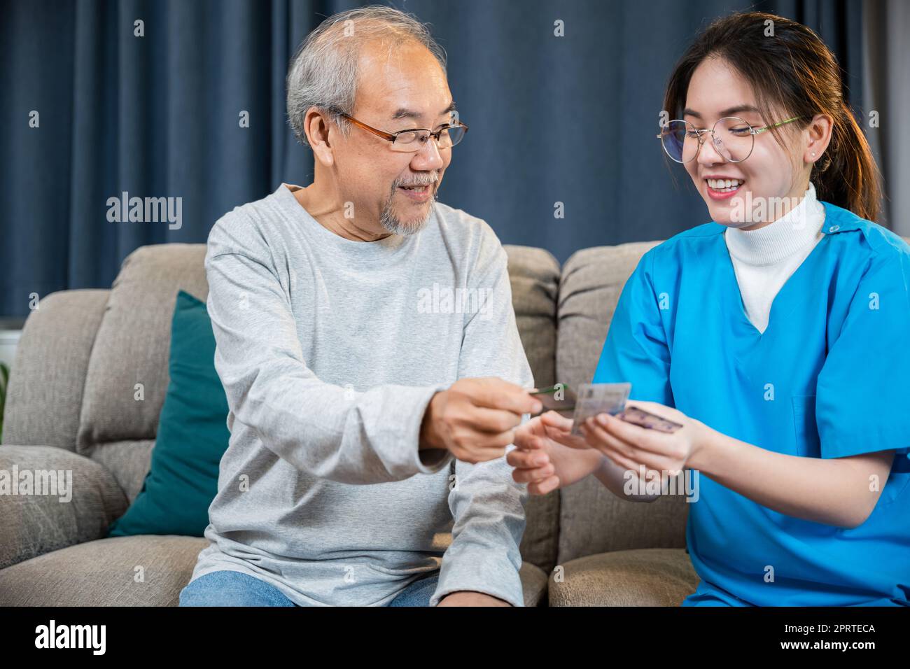 Infermiera donna mostra il farmaco prescritto a un uomo anziano a casa di cura Foto Stock
