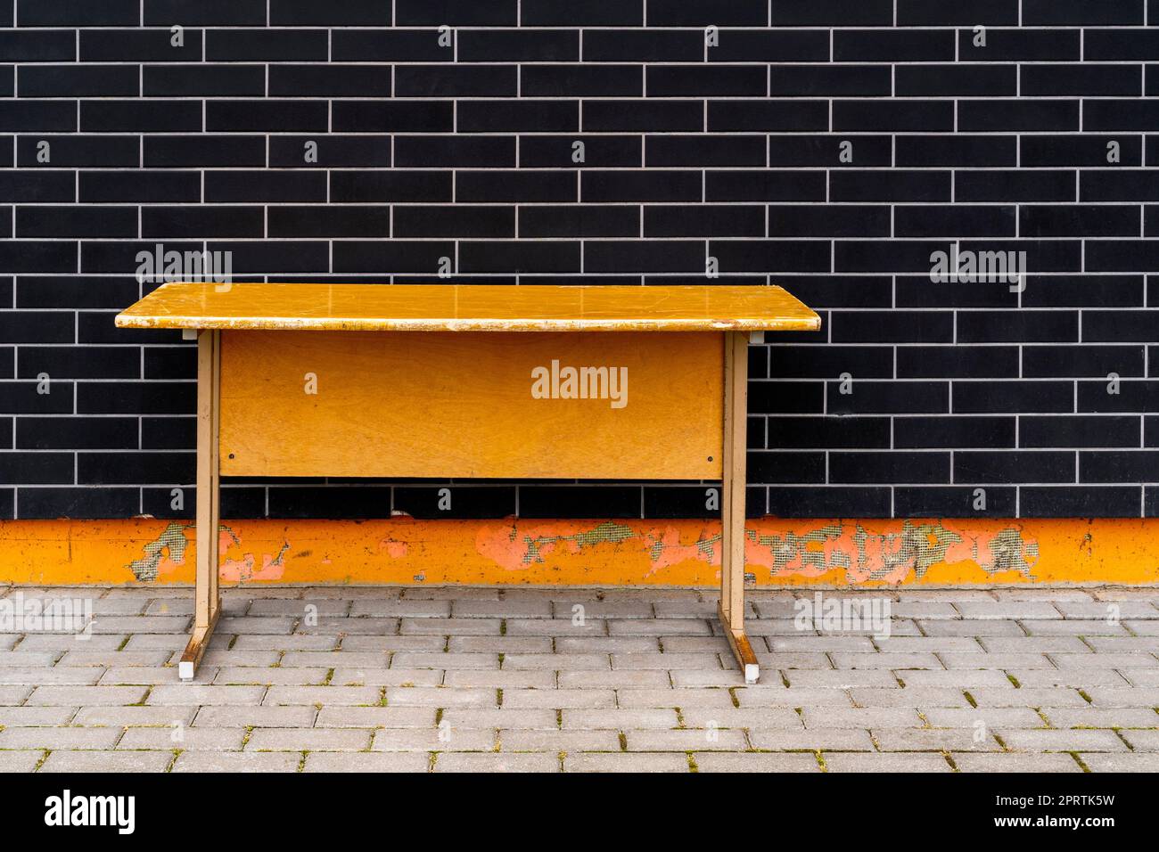 Vecchio banco della scuola accanto al muro della scuola Foto Stock