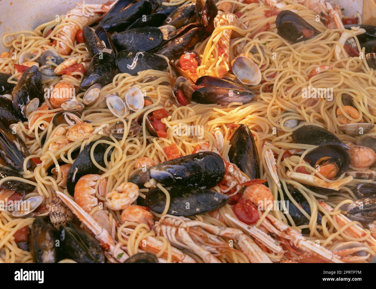 Spaghetti italiani allo scoglio, primi piani di pasta con frutti di mare e pomodori in padella Foto Stock