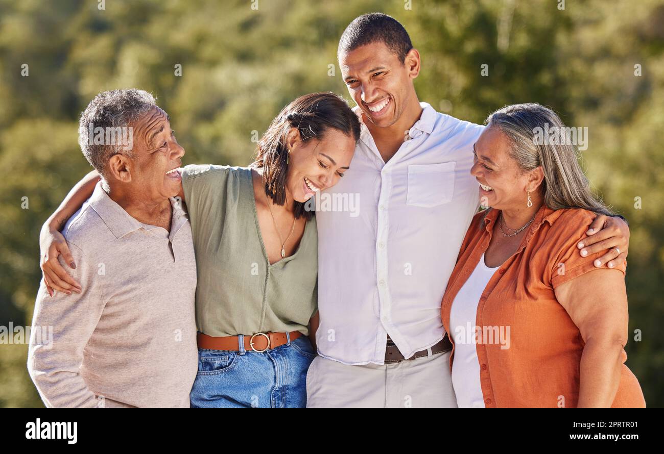 Felice, abbracciate e sorridete, una famiglia adulta in un parco in piedi insieme. Madre, padre, figli cresciuti ridendo. Felicità, amore e natura, uomo e donna con coppia anziana nella natura ad un evento all'aperto. Foto Stock