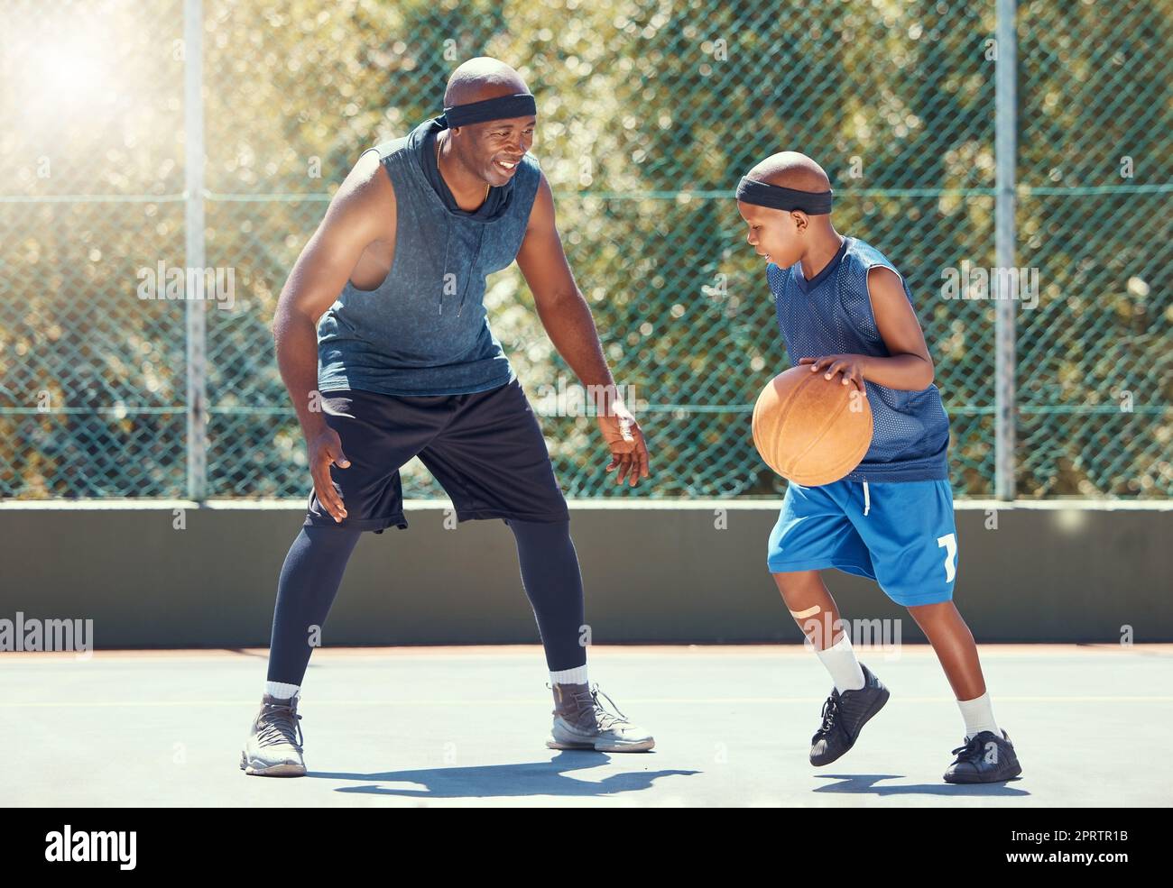 Sport, famiglia e pallacanestro con papà e figlio che si allenano sul campo all'aperto per il tempo libero, il fitness e il divertimento. Uomo nero e bambino facendo esercizio e allenamento giocando a un gioco per la salute e l'allenamento Foto Stock