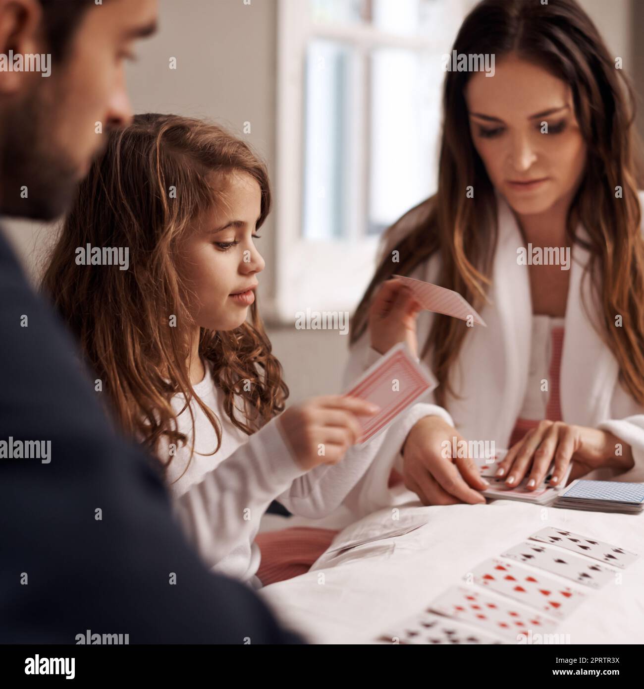 Il mio turno, una giovane famiglia che gioca a carte insieme a casa. Foto Stock