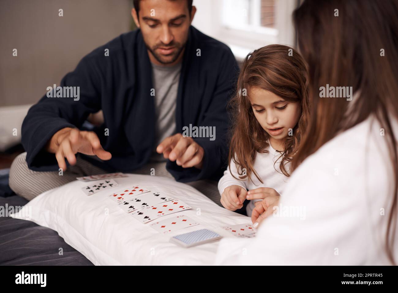 Im vado a vincere questo round. Una giovane famiglia che gioca le carte insieme a casa. Foto Stock