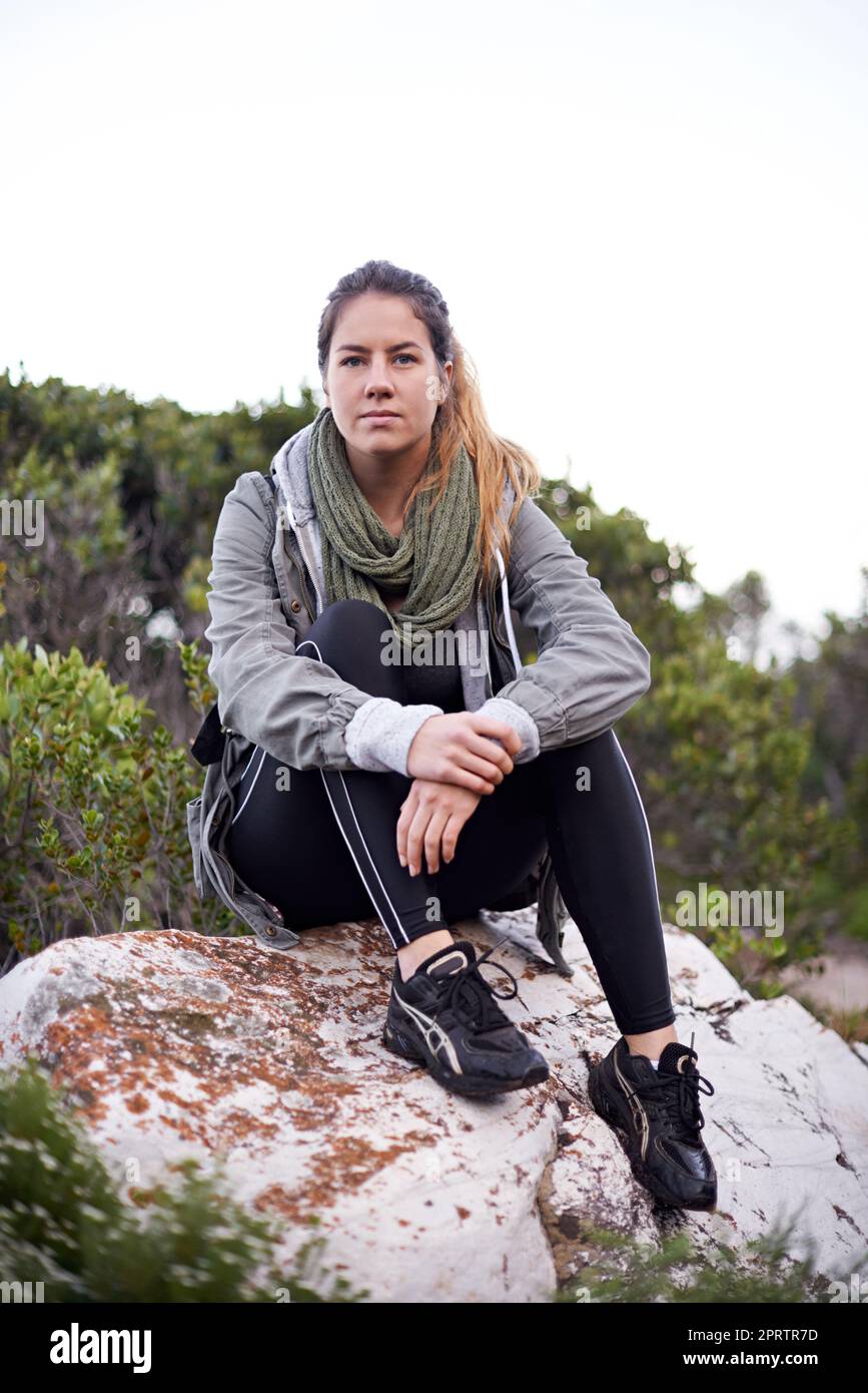 Prendendosi una pausa dalla sua camminata della natura. Ritratto di una giovane donna attraente fare una pausa mentre fuori trekking. Foto Stock