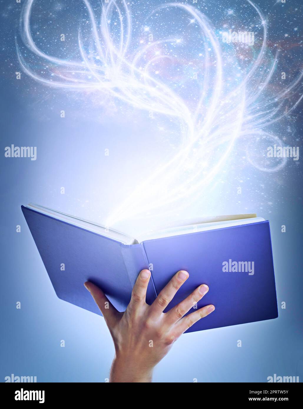 Immergiti in nuovi mondi magici, una mano che tiene in mano un libro di storie aperto con la luce che ne emana. Foto Stock