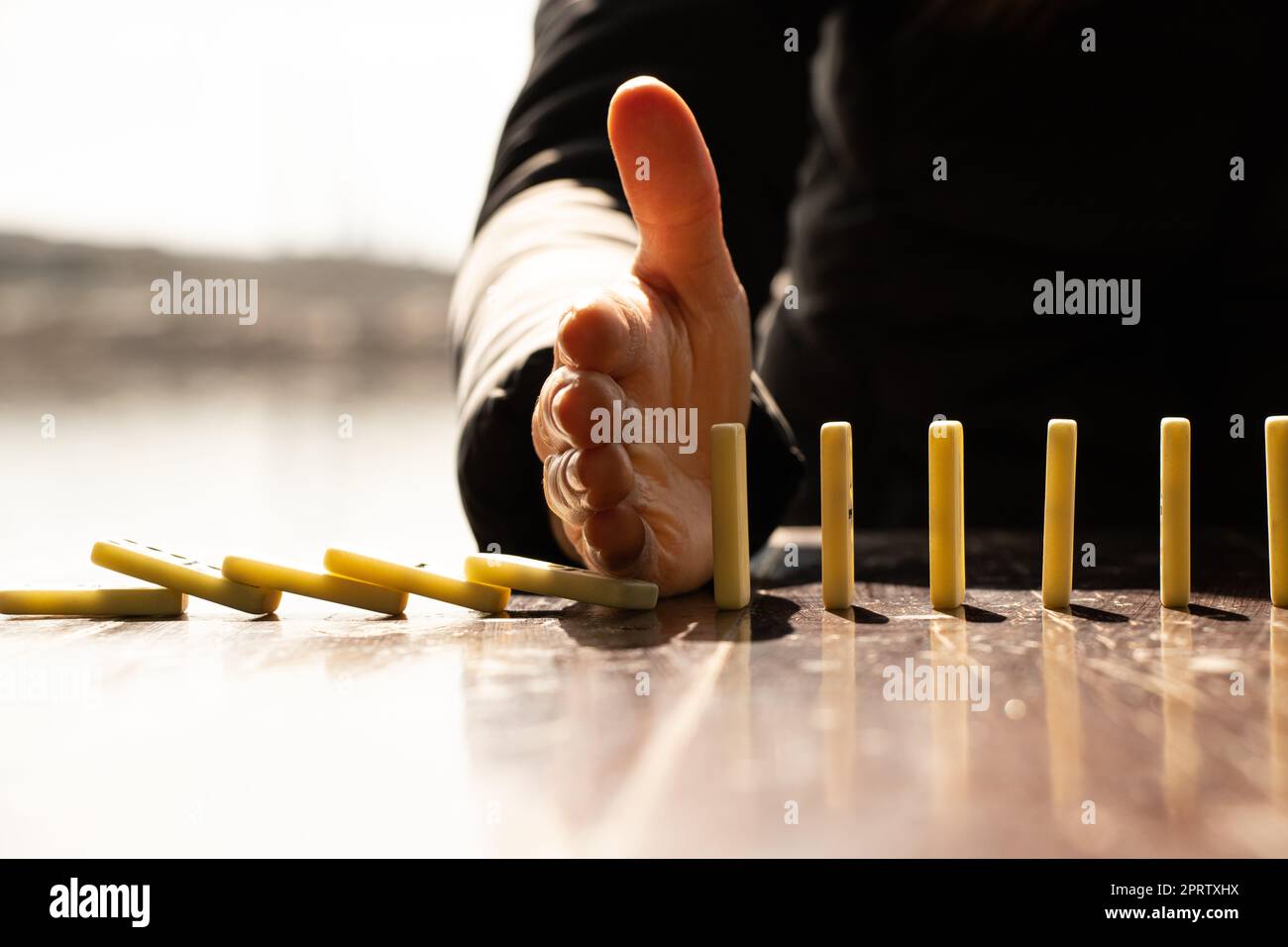 La mano delle donne e il domino su un tavolo di legno al sole nei parchi Foto Stock