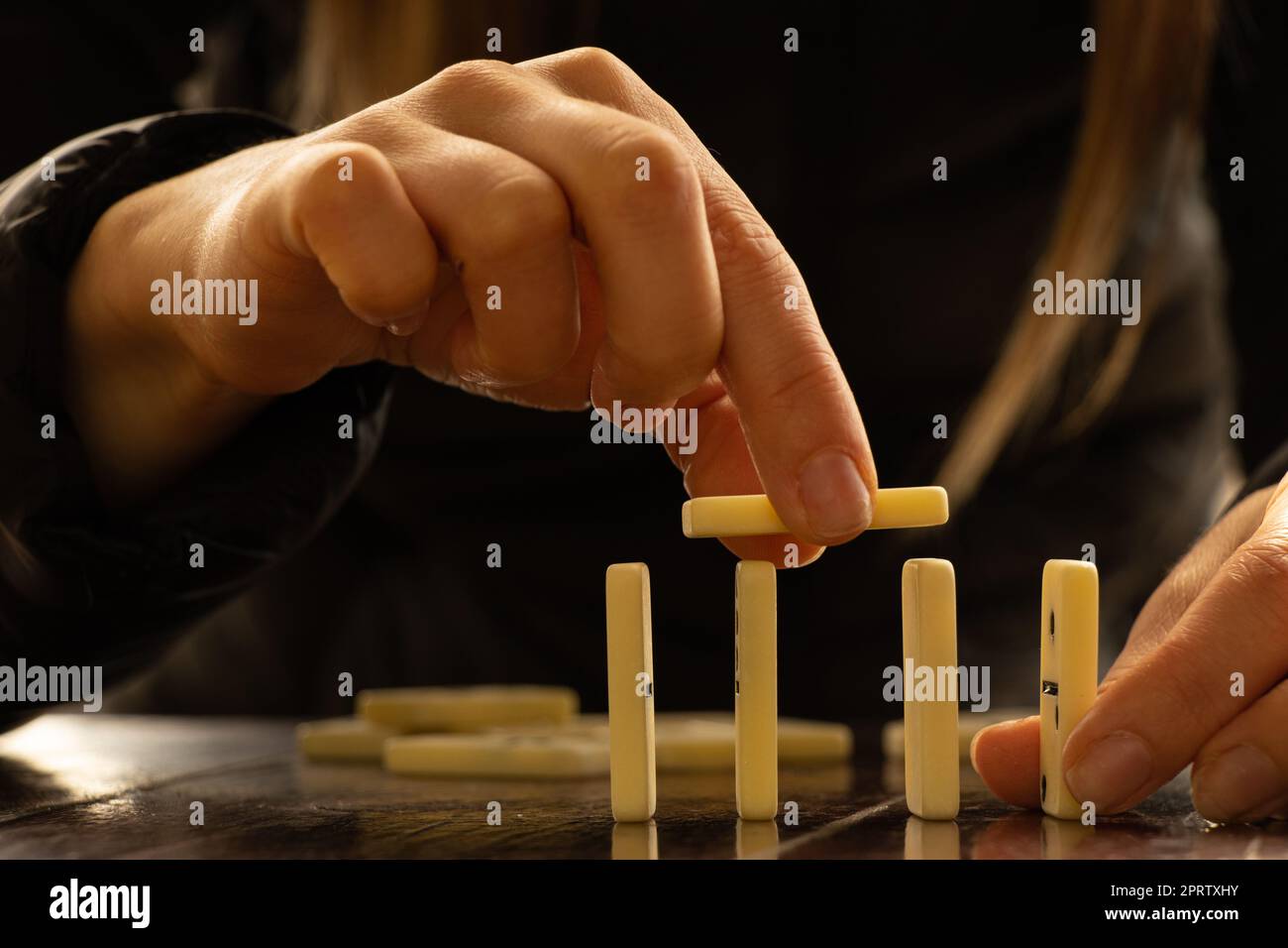 La mano delle donne e il domino su un tavolo di legno al sole nei parchi Foto Stock