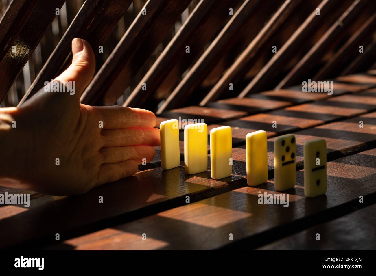 La mano delle donne e il domino su un tavolo di legno al sole nei parchi Foto Stock