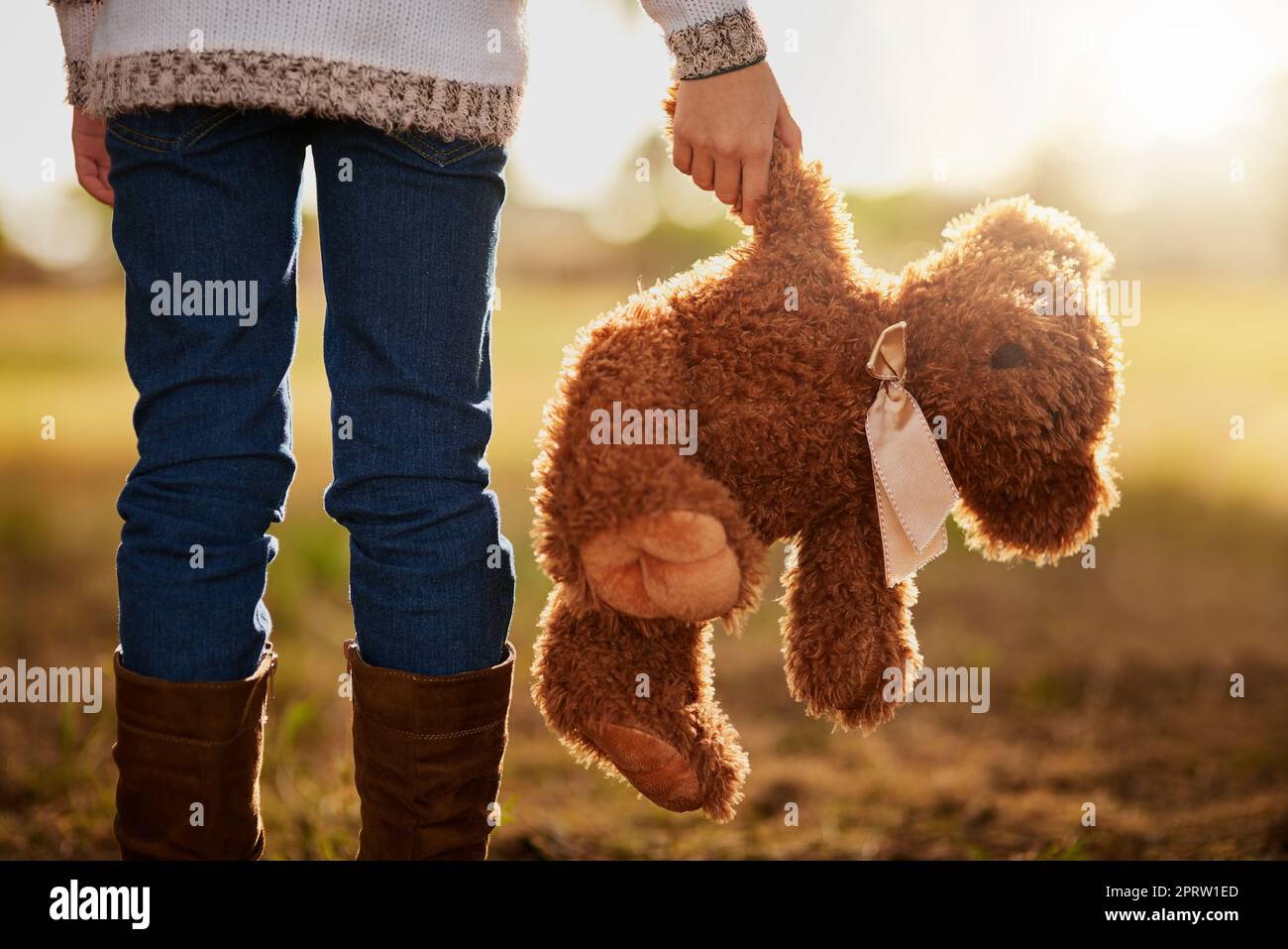 Nessuna infanzia è completa senza un orso preferito. Ripresa da dietro di una bambina non identificabile che cammina nel parco con il suo orsacchiotto Foto Stock