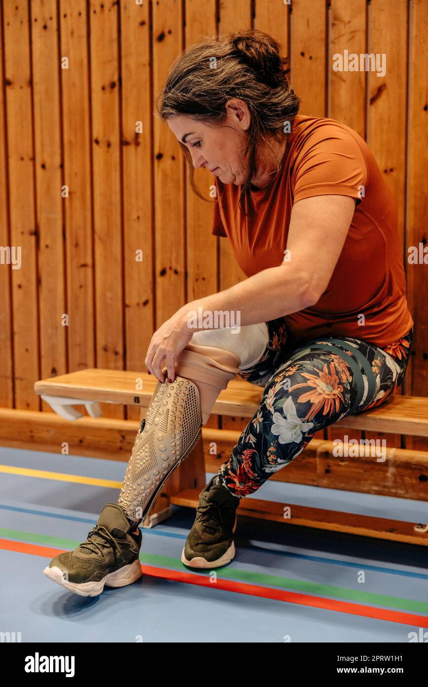 Atleta femminile che indossa un arto artificiale mentre si siede sulla panca al campo sportivo Foto Stock