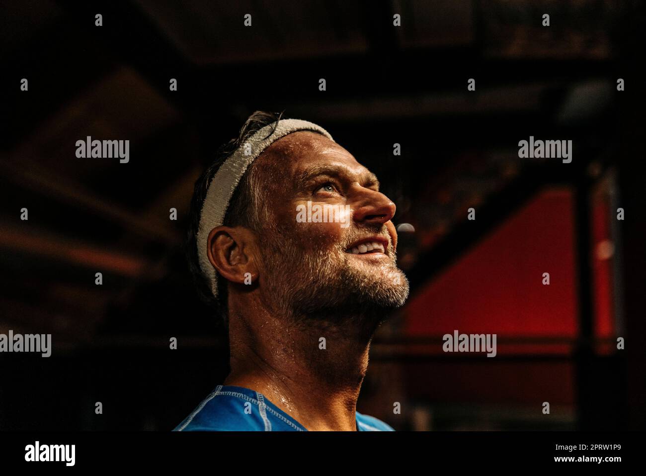 Atleta sorridente che indossa la fascia mentre si contempla il campo sportivo Foto Stock