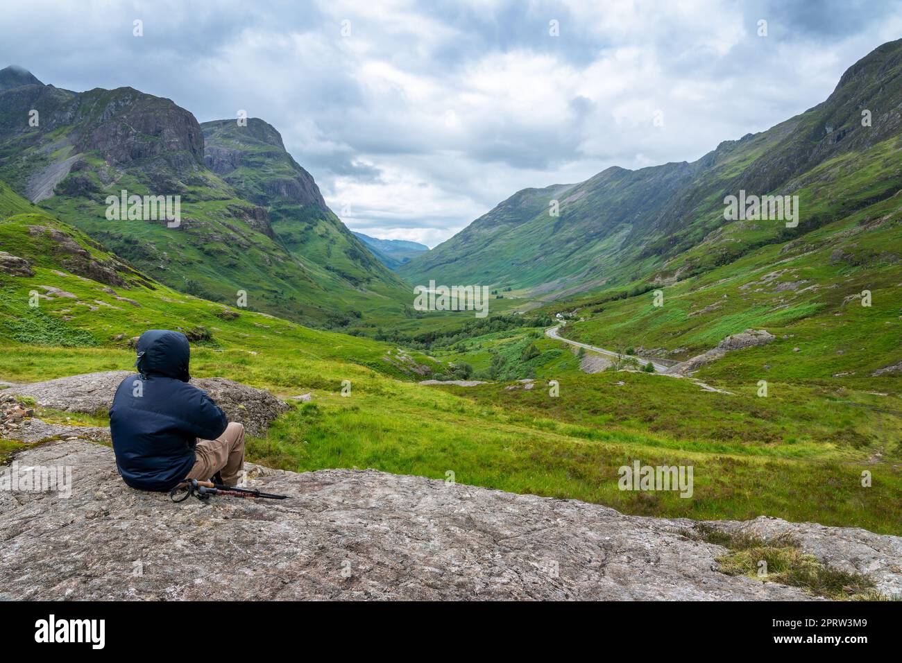 Un escursionista irriconoscibile che guarda alla valle di Glencoe in estate, Highlands of Scotland, UK Foto Stock