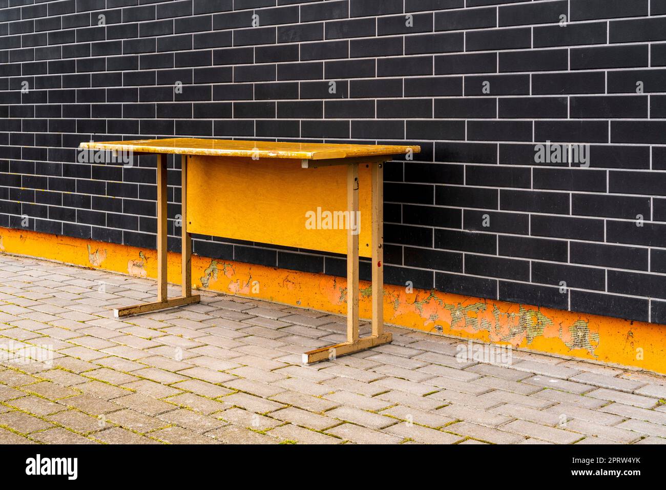 Vecchio banco scuola in legno vicino al muro dell'edificio scolastico Foto Stock