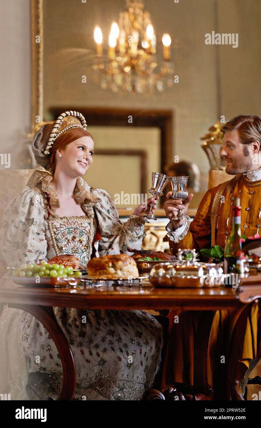 Godendo dei vantaggi della nascita reale. Un re regale e una regina che gustano un pasto insieme. Foto Stock