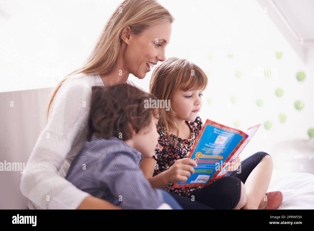 Legarsi sopra un buon libro di storia. Una madre che legge con i suoi bambini nel paese. Foto Stock