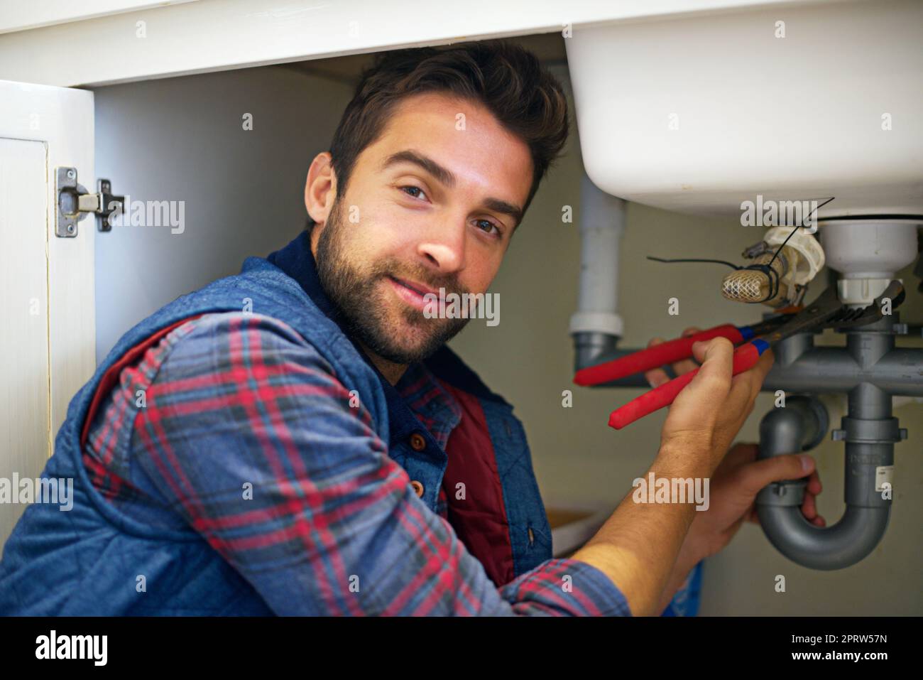 Dovrei risolvere questo problema in un istante: Un idraulico che fissa un tubo. Foto Stock
