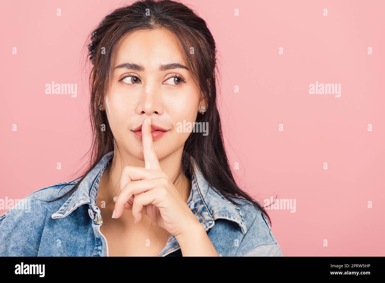 donna indossare jeans sorriso stand facendo il dito sulle labbra bocca silenziosa gesto tranquillo Foto Stock