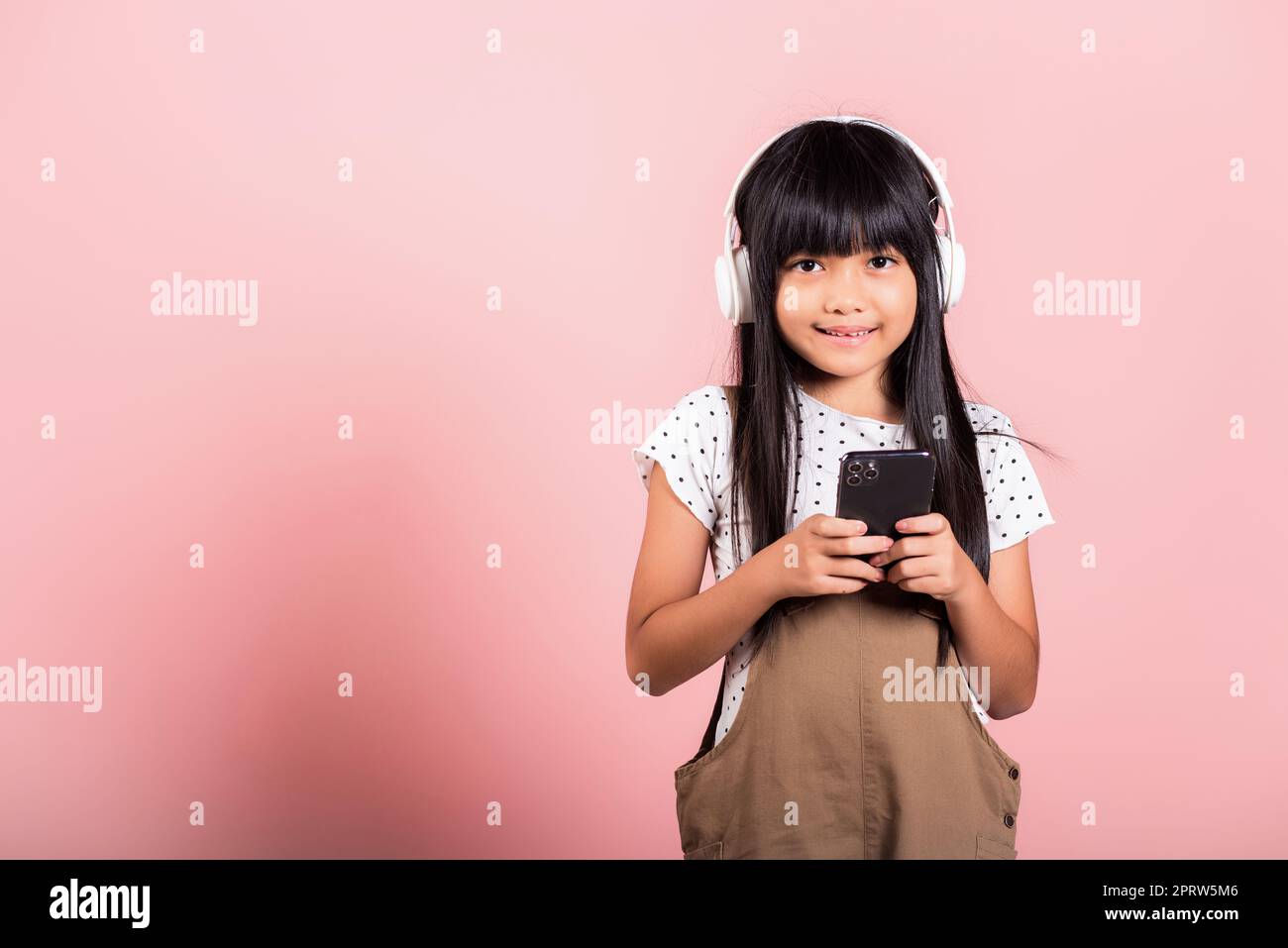Bambino asiatico da 10 anni che ascolta la musica dal telefono cellulare indossare cuffie wireless Foto Stock