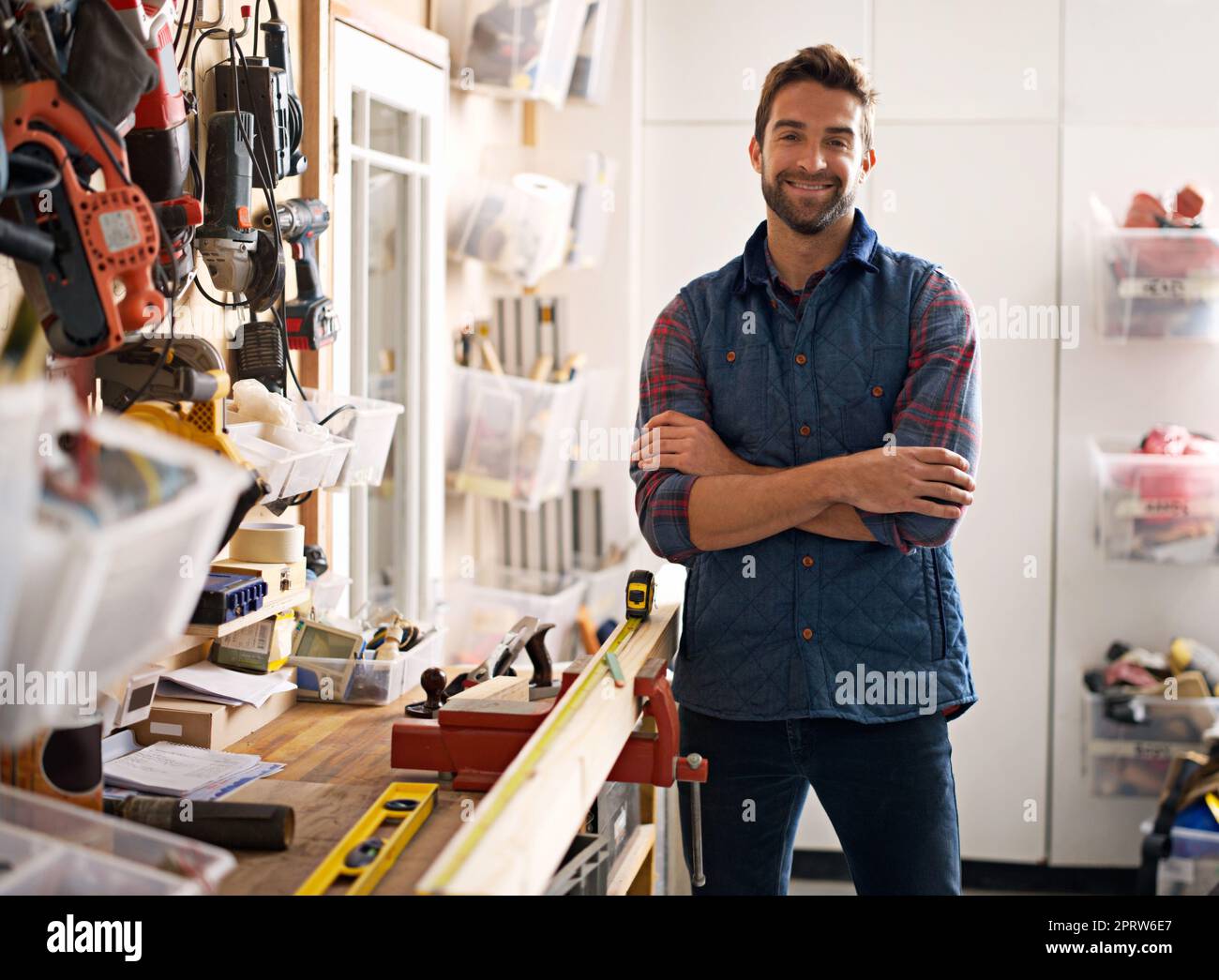 Mi chiami, onorevole Fixit. Ritratto di un bel giovane handyman in piedi davanti ai suoi utensili da lavoro. Foto Stock