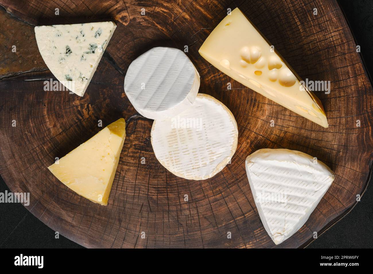 Vista dall'alto dell'assortimento di formaggio brie, camembert, parmigiano e gouda su tagliere di legno. Foto Stock