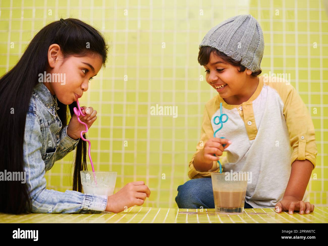 È tutto sullo slurp. Un fratello e una sorella carini che bevono i milkshakes con le cannucce. Foto Stock