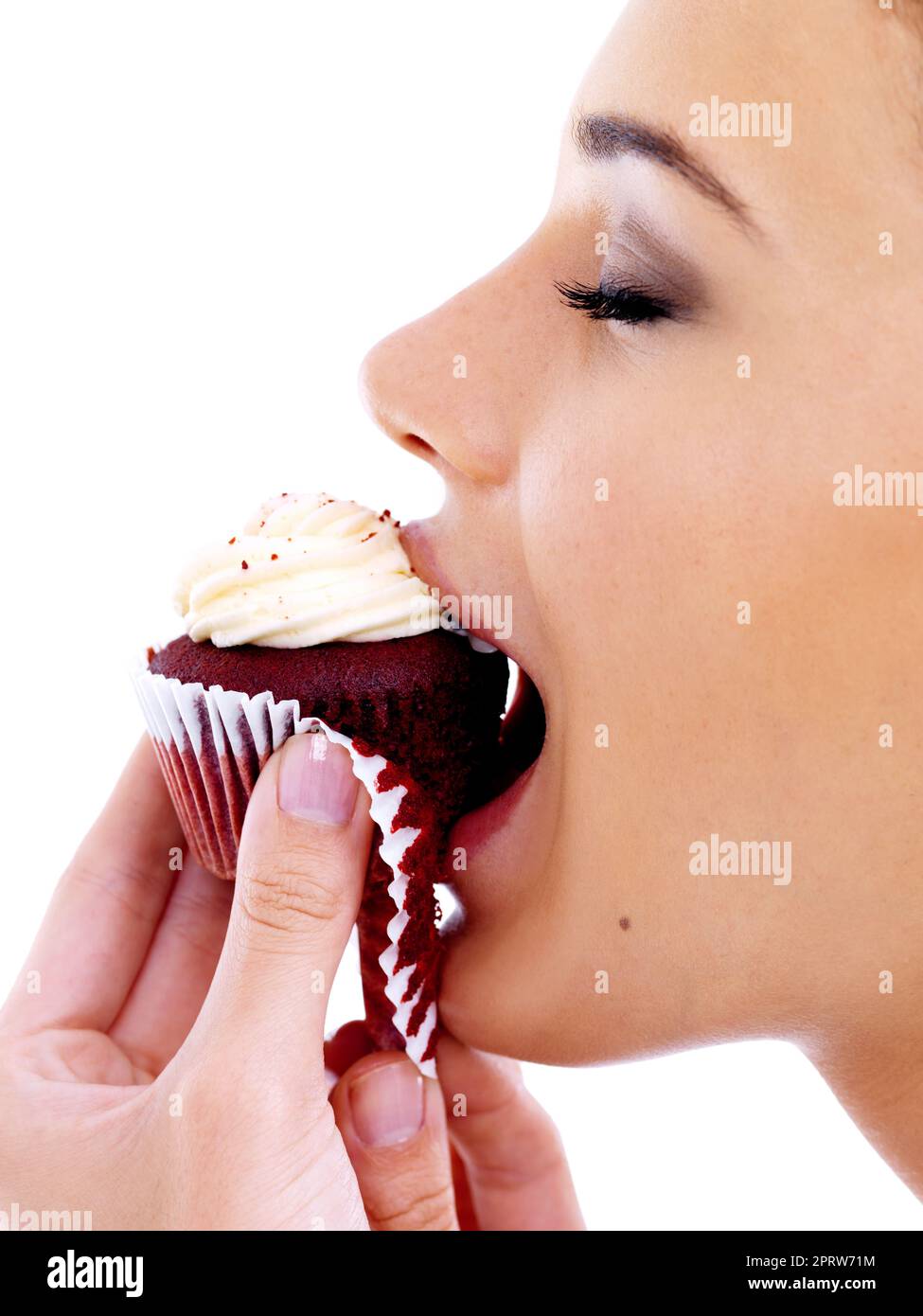 Cielo di velluto rosso. Studio shot di una bella giovane donna godendo di un cupcake di velluto rosso. Foto Stock