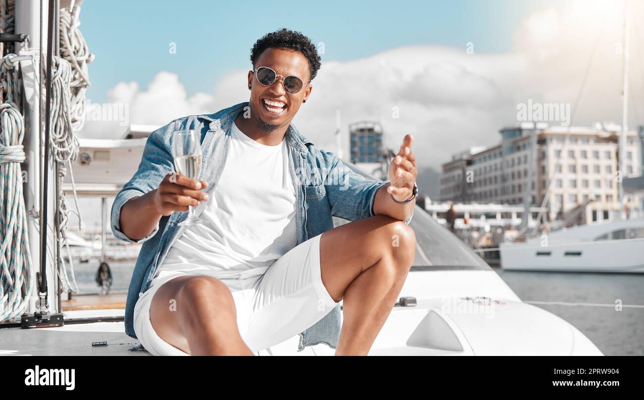 Champagne drink, vacanza in yacht e uomo in vacanza a Miami, felice su una barca al sole e in estate internazionale. Ritratto della persona africana sorridere, emozionato e rilassato sul ponte di lusso al sole Foto Stock