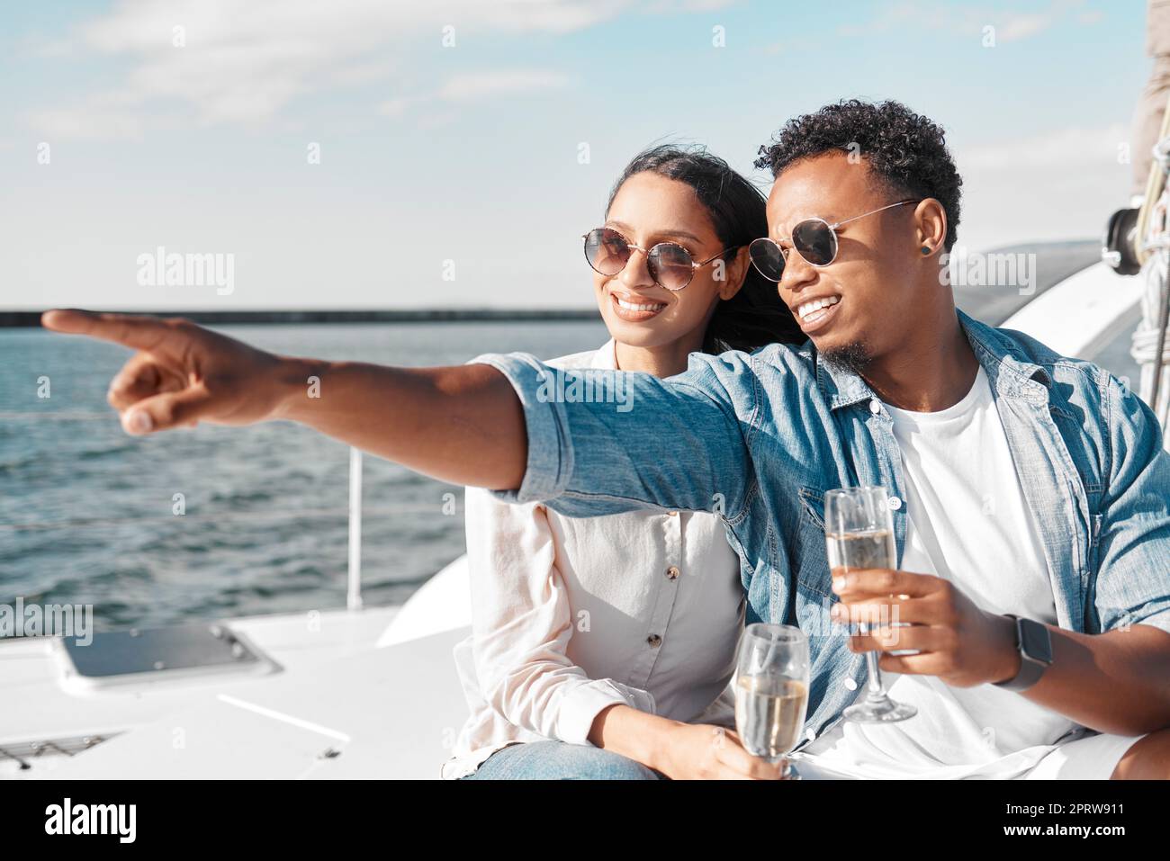 Barca, yacht e coppia con champagne al sole e al mare d'estate per celebrare l'amore insieme. Sorriso felice di gente con l'acqua dell'oceano, le onde blu e il sole nella natura per una celebrazione di anniversario Foto Stock