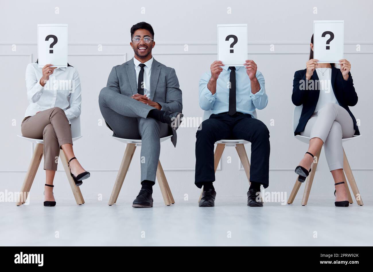 Un uomo in fila al momento dell'assunzione sorride per il colloquio, in sala d'attesa per vedere il manager o il capo. Un maschio professionista in gruppo di persone con un punto interrogativo o un poster per il reclutamento Foto Stock