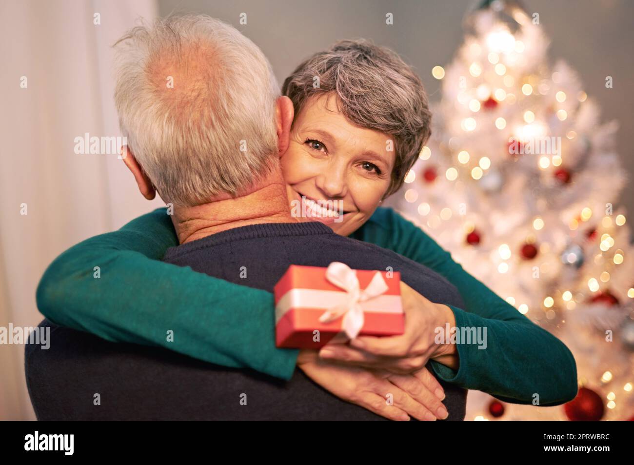 Il mio Babbo Natale. Ritratto di una donna matura felice che abbraccia il marito dopo aver ricevuto un regalo di Natale da lui. Foto Stock