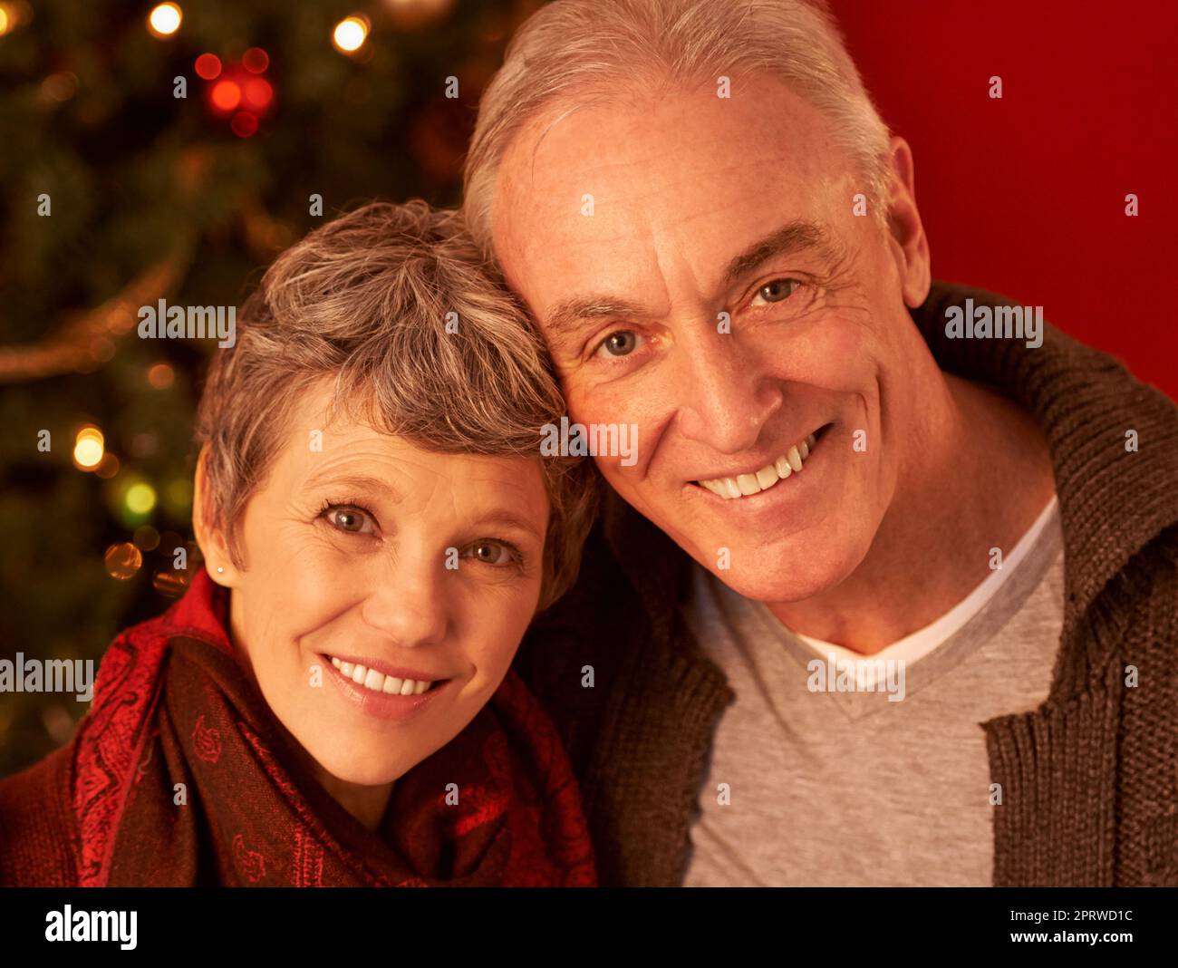 È il periodo più bello dell'anno. Un ritratto corto di una coppia matura felice davanti ad un albero di Natale. Foto Stock