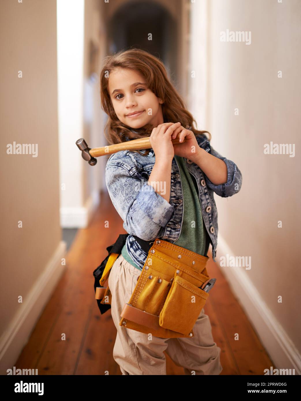 Può risolvere il problema. Ritratto di una giovane ragazza che indossa una cintura portautensili e tiene un martello. Foto Stock