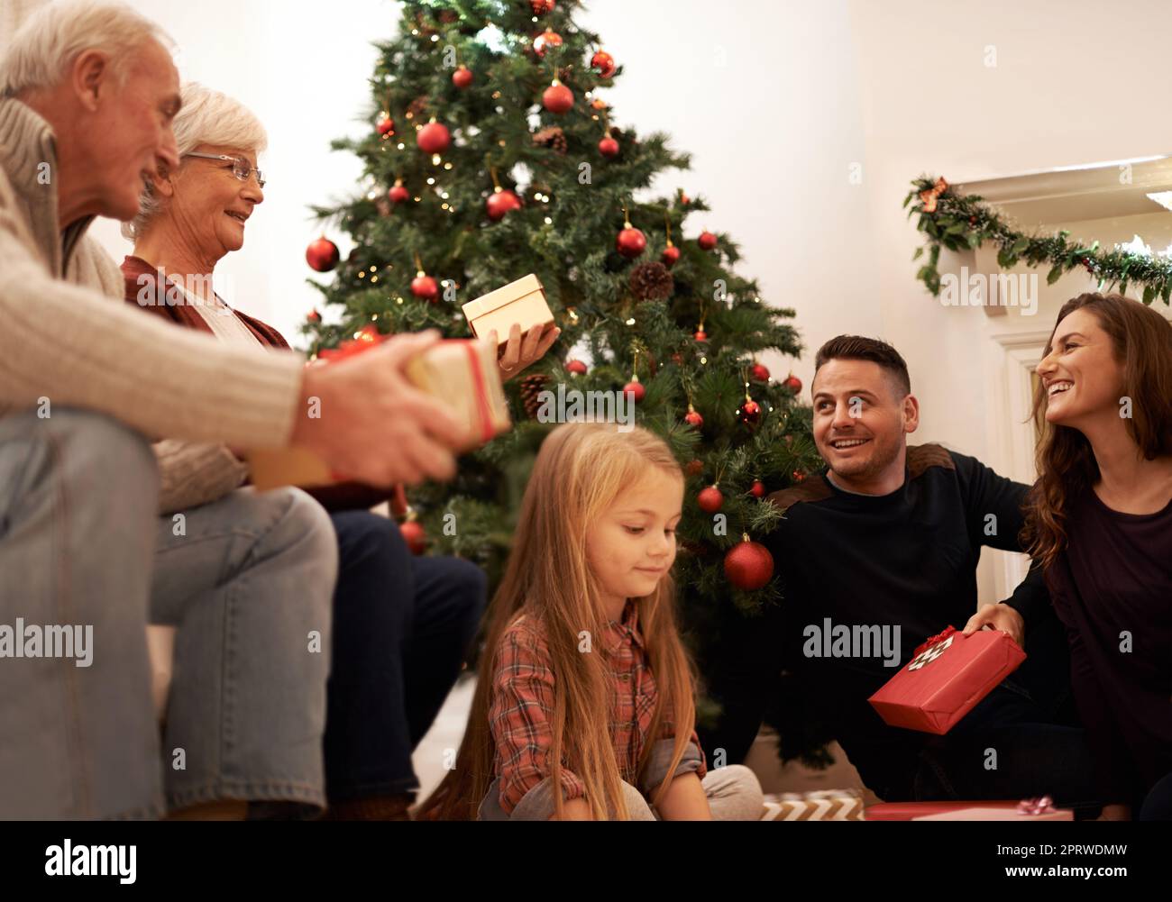 Piena di gioia di dare. Una famiglia multigenerazionale che si scambiano regali a Natale. Foto Stock