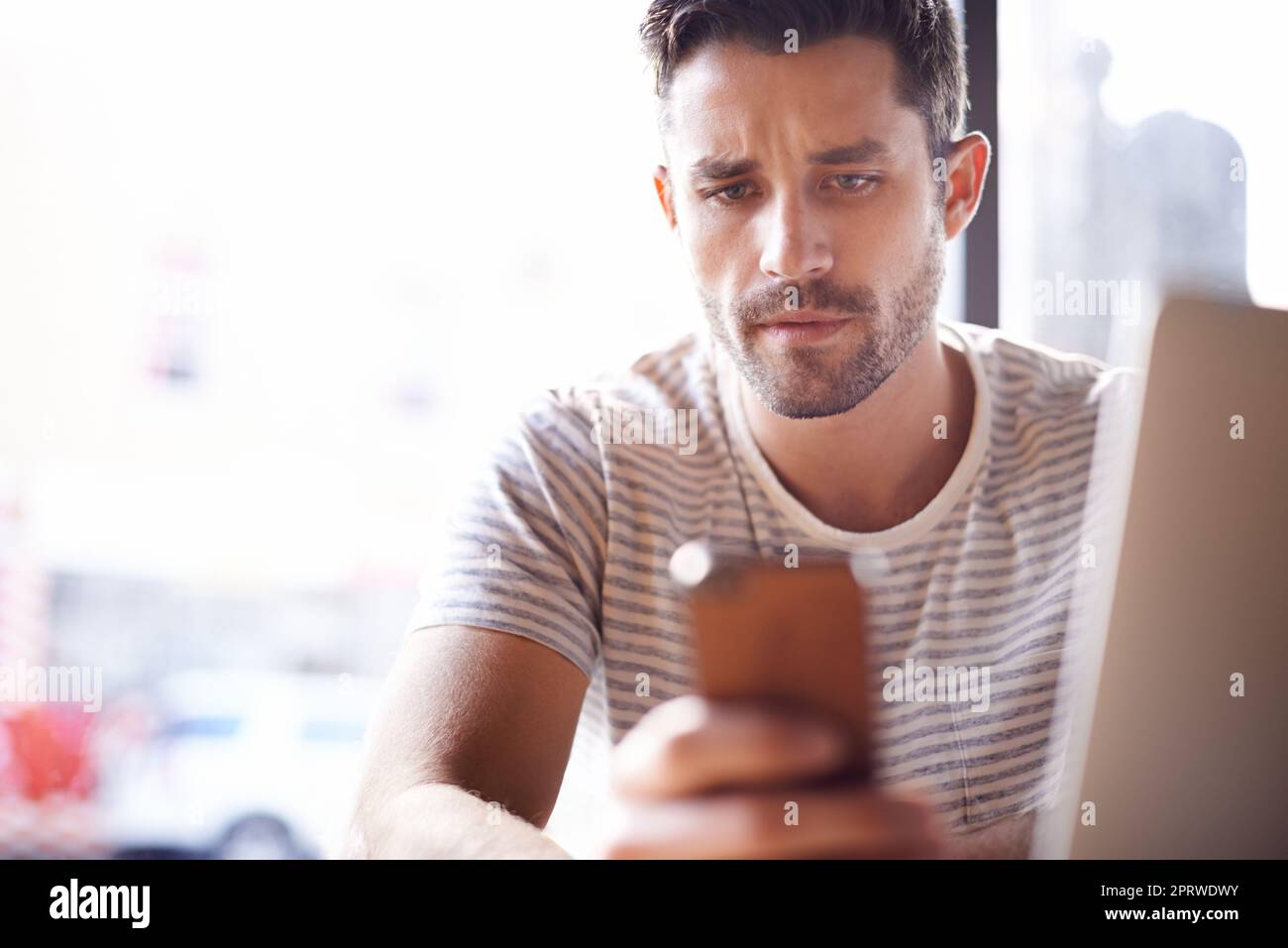 Organizzare le sue riunioni di lavoro per il giorno successivo. Un giovane imprenditore al telefono mentre si siede con il computer portatile in una caffetteria. Foto Stock