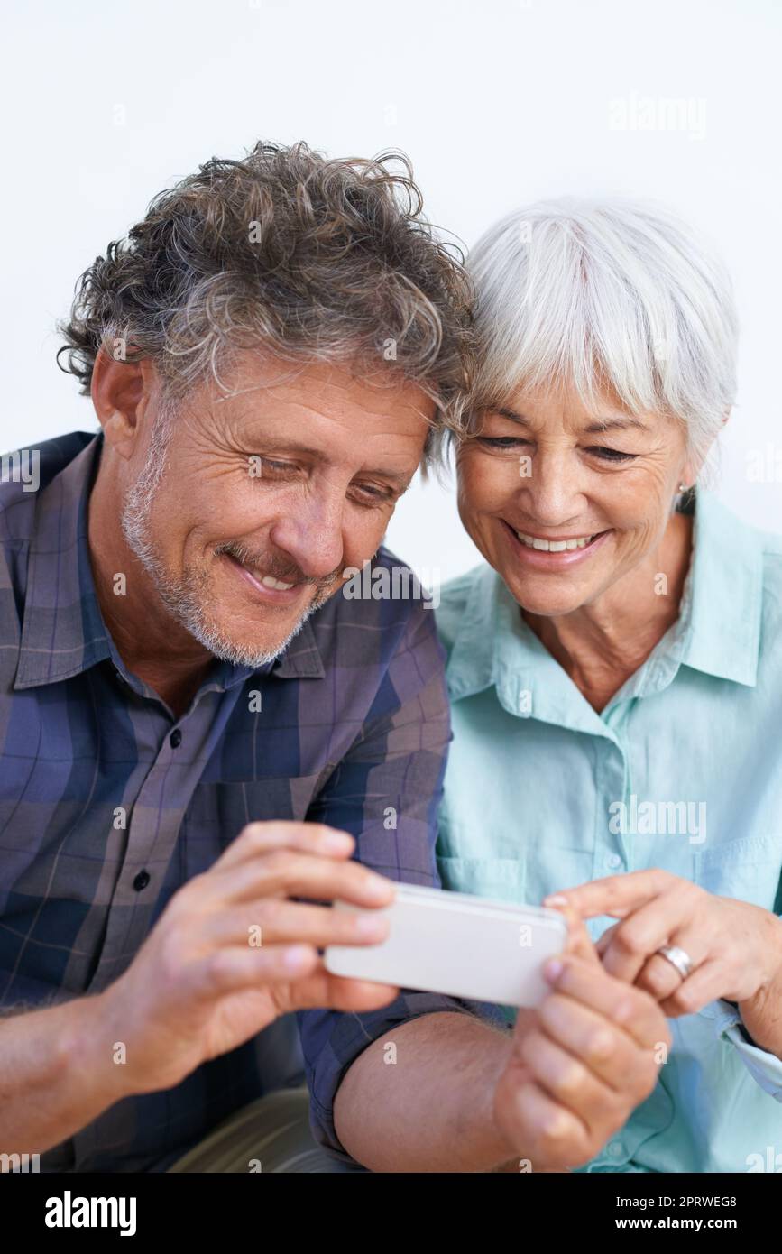 Tornate all'altra. Una coppia felice e anziana che guarda un cellulare. Foto Stock
